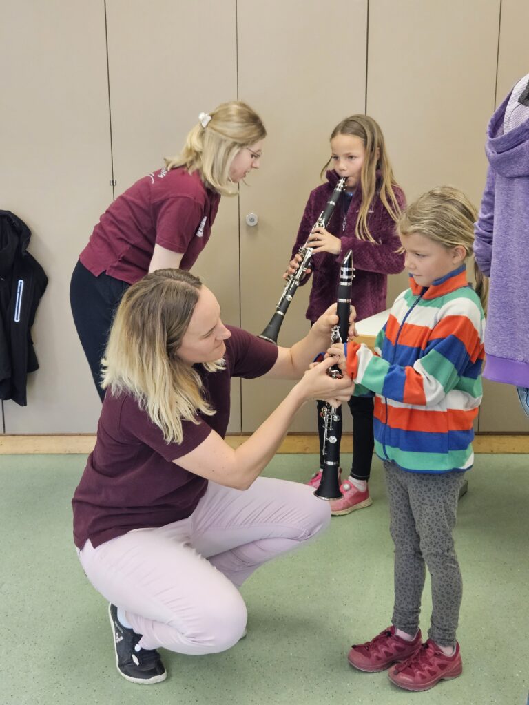 zwei Mädchen probieren unter Anleitung zweier Musikantinnen die Klarinette aus
