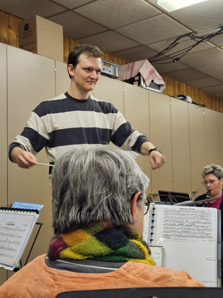 Luca Belz mit halberhobenen Armen beim Dirigieren