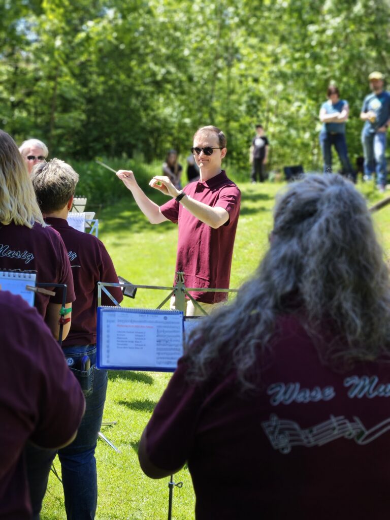 Luca mit Sonnenbrille mit erhobenen Armen beim Dirigieren