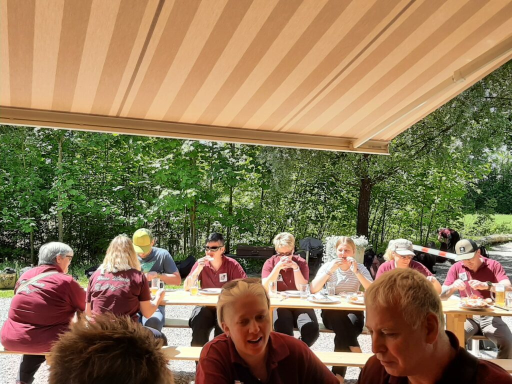 Musikanten sitzen an Tischen und plaudern unter einer Sonnenstore