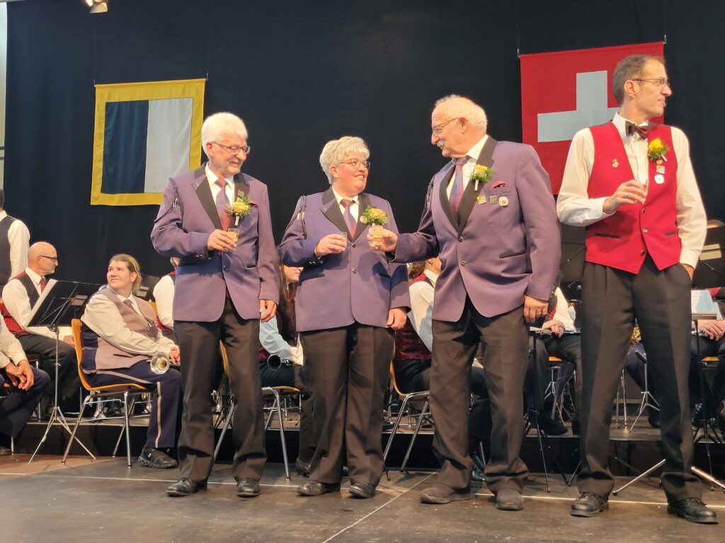 Beat Blaser, Barbara Flückiger, Niklaus Schütz (v.l.n.r.) auf der Bühne und prosten sich zu