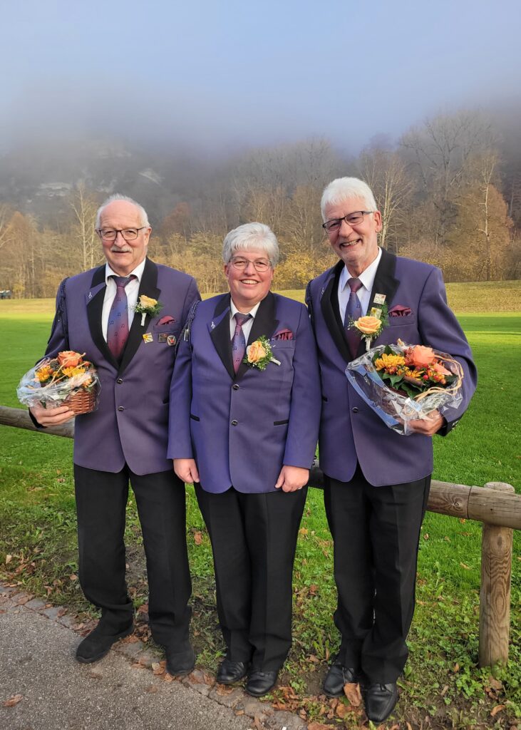 Niklaus Schütz, Barbara Flückiger und Beat Blaser (v.l.n.r.) draussen, die Herren mit Blumensträussen