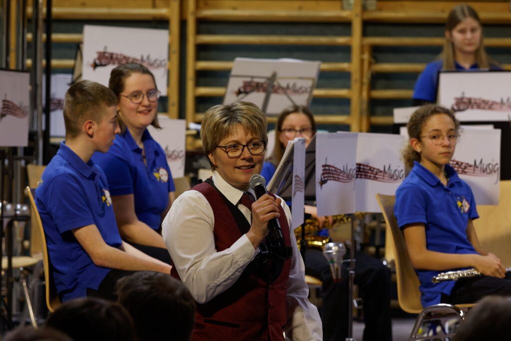 Kathrin Rösch am Mikrofon, im Hintergrund Jungmusikanten